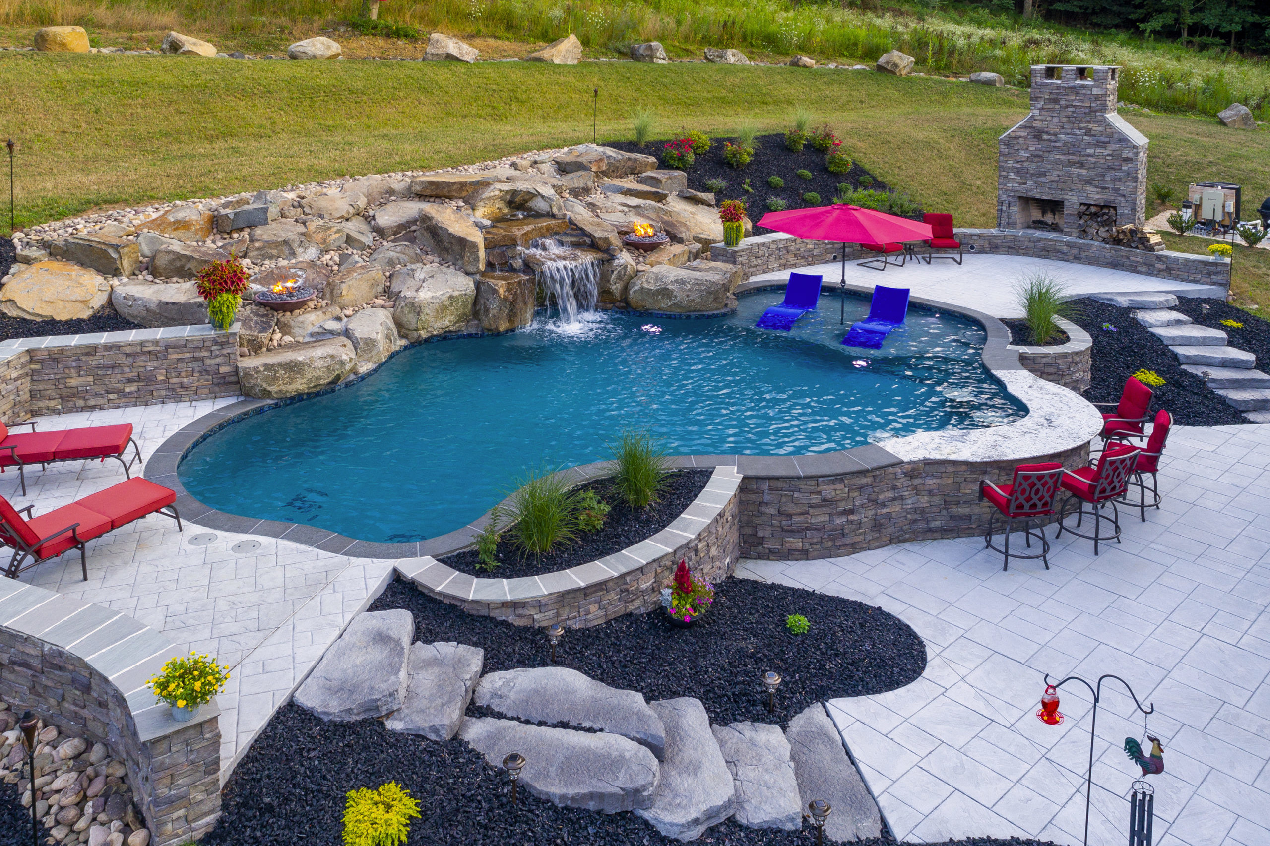 Wavy pool with red chairs and umbrellas