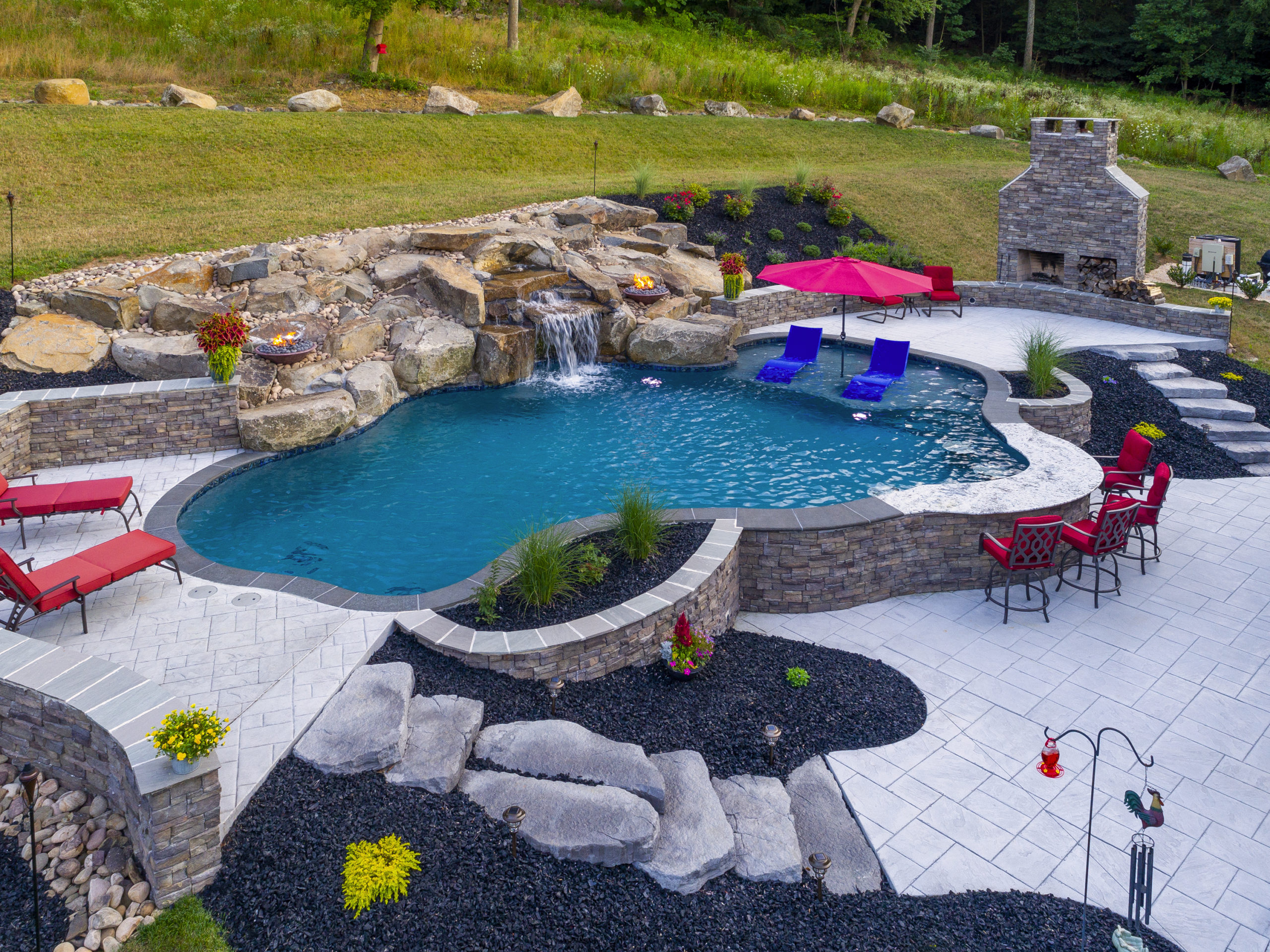 Wavy pool with red chairs and umbrellas